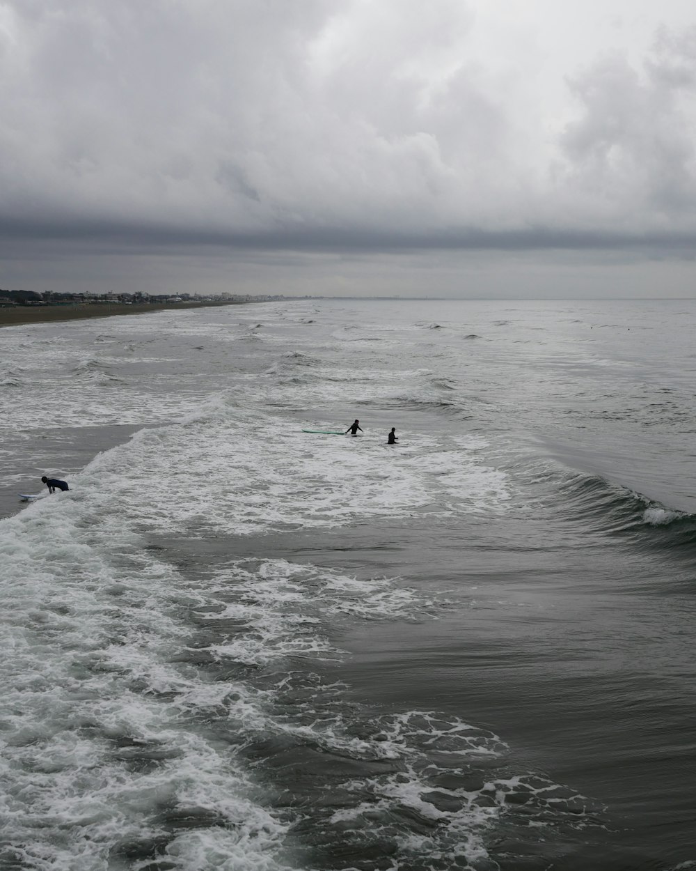 Un par de personas montando tablas de surf encima de una ola