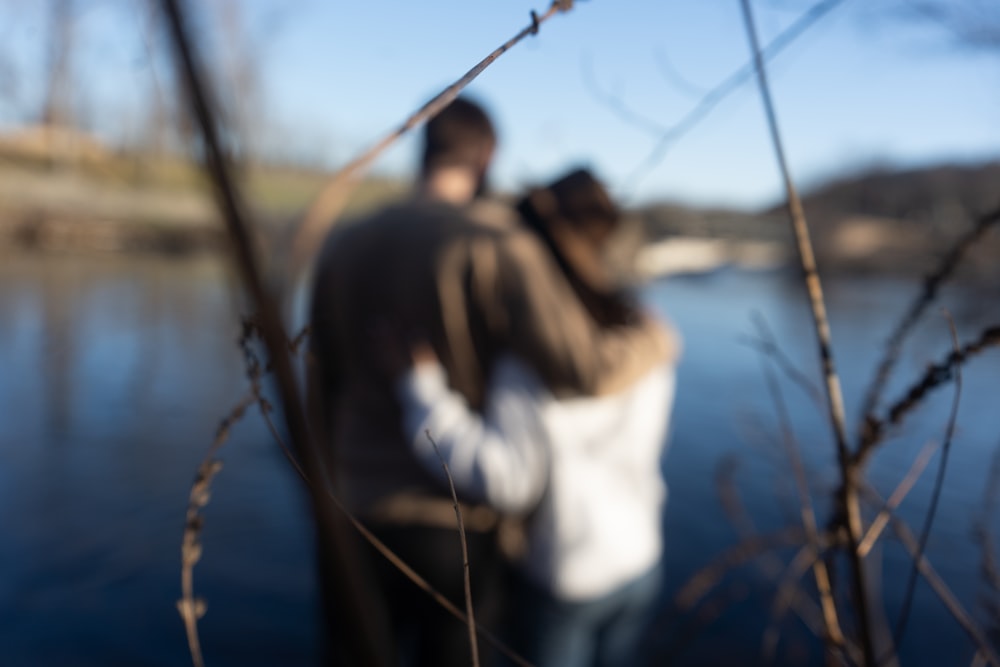 a blurry photo of two people standing next to a body of water