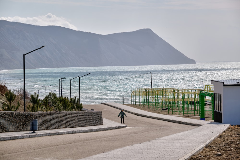 a person riding a skateboard down a street next to the ocean