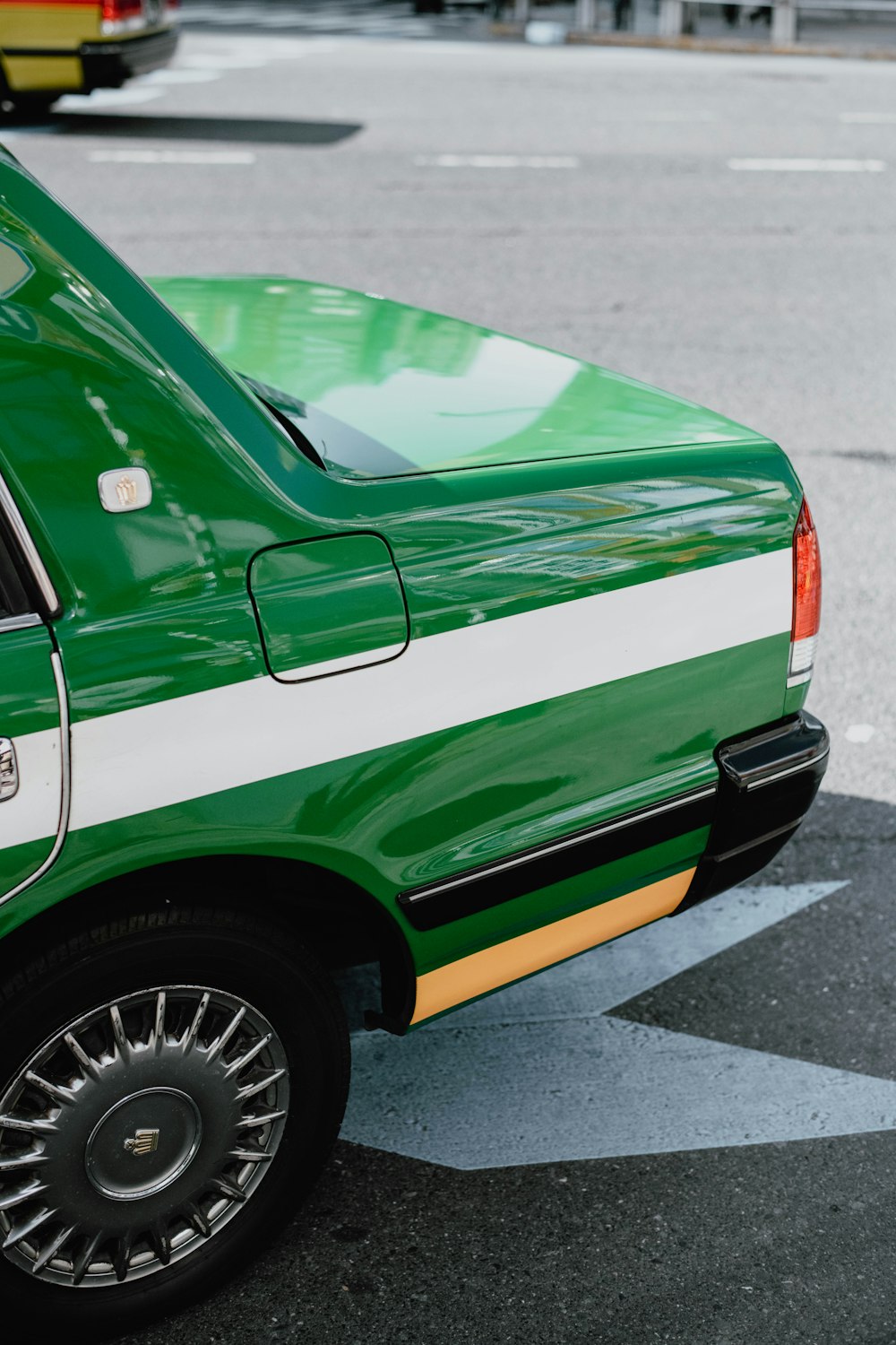 a green and white car parked on the side of the road