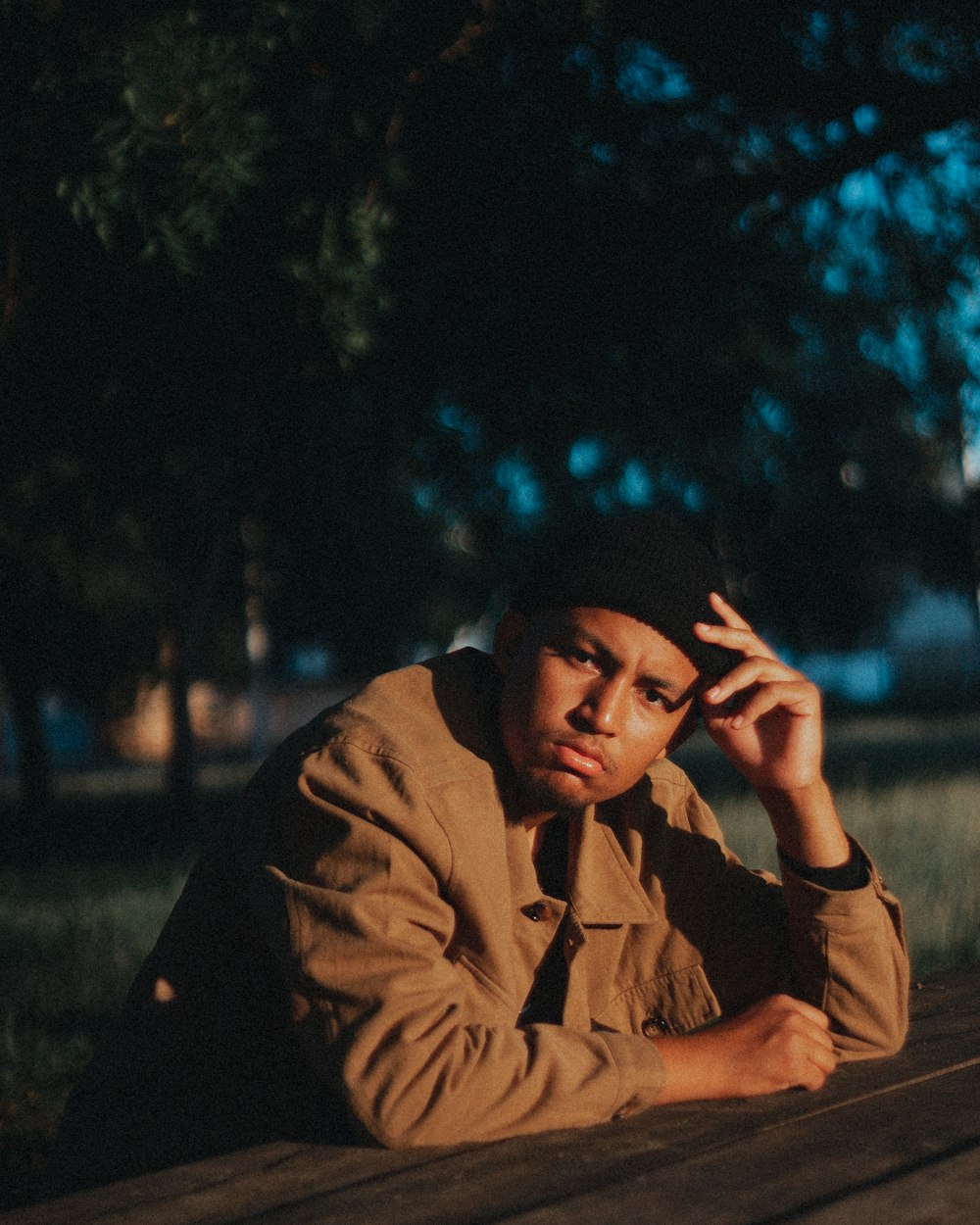 a man sitting on a picnic table talking on a cell phone