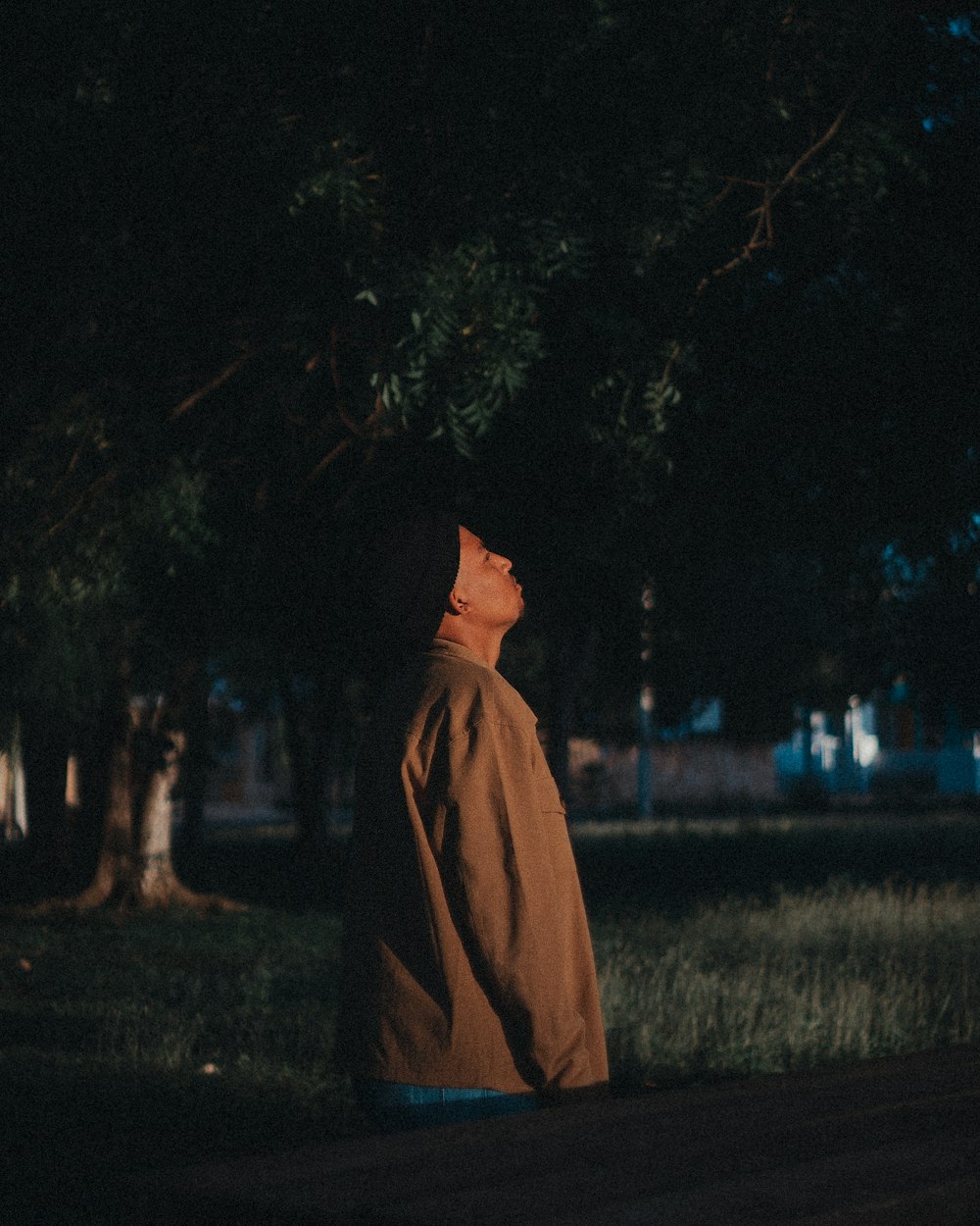 a man sitting on a bench in a park at night