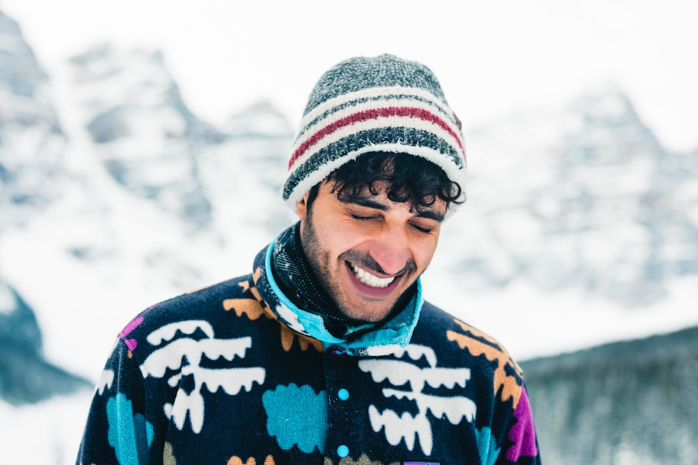 a smiling man in a colorful sweater and hat