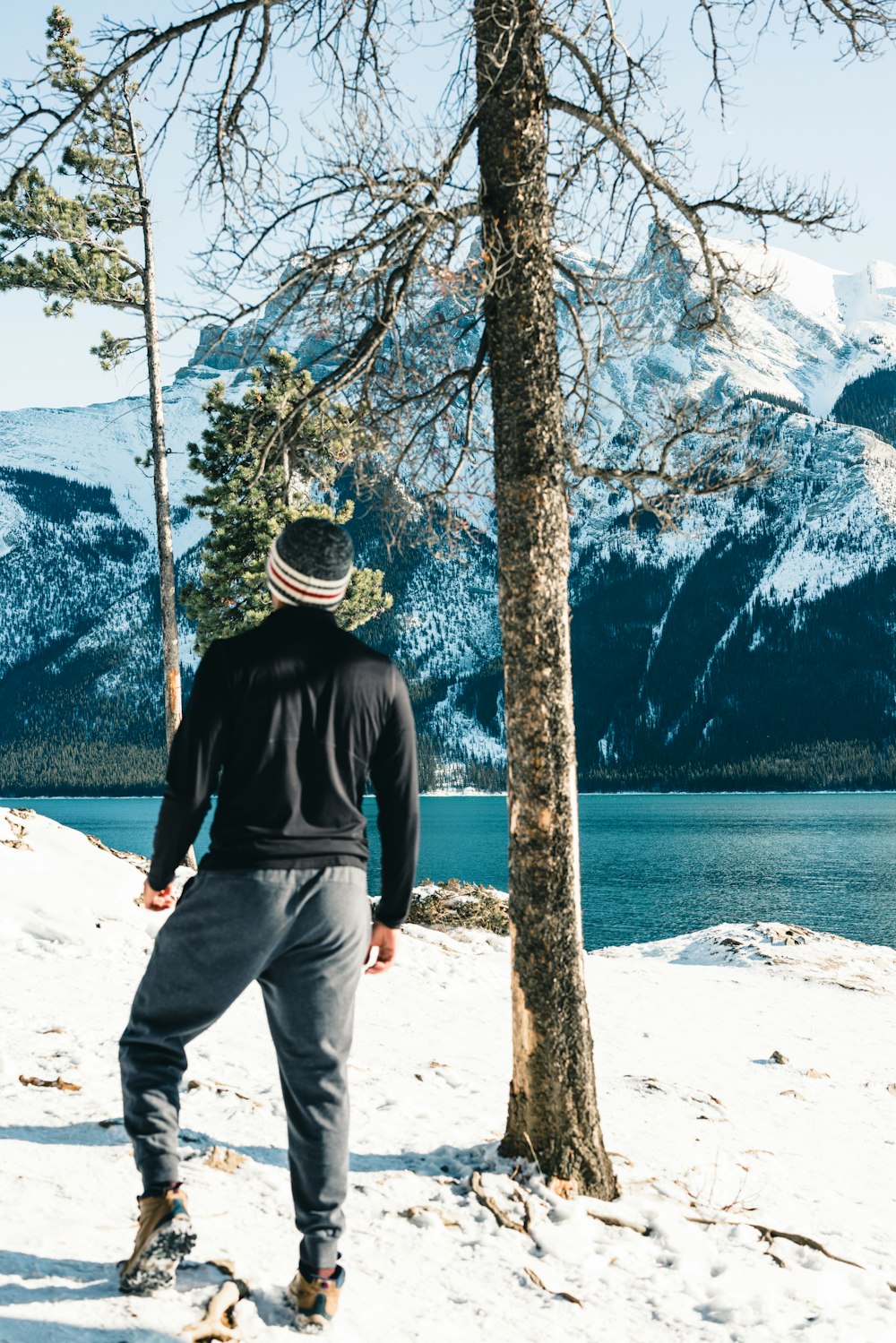 a man standing next to a tree in the snow