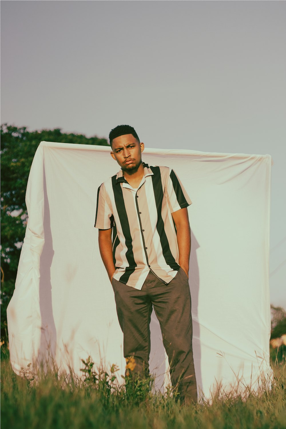 a man standing in a field next to a white sheet