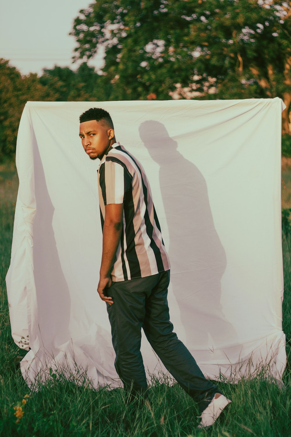 a man standing in a field next to a white sheet