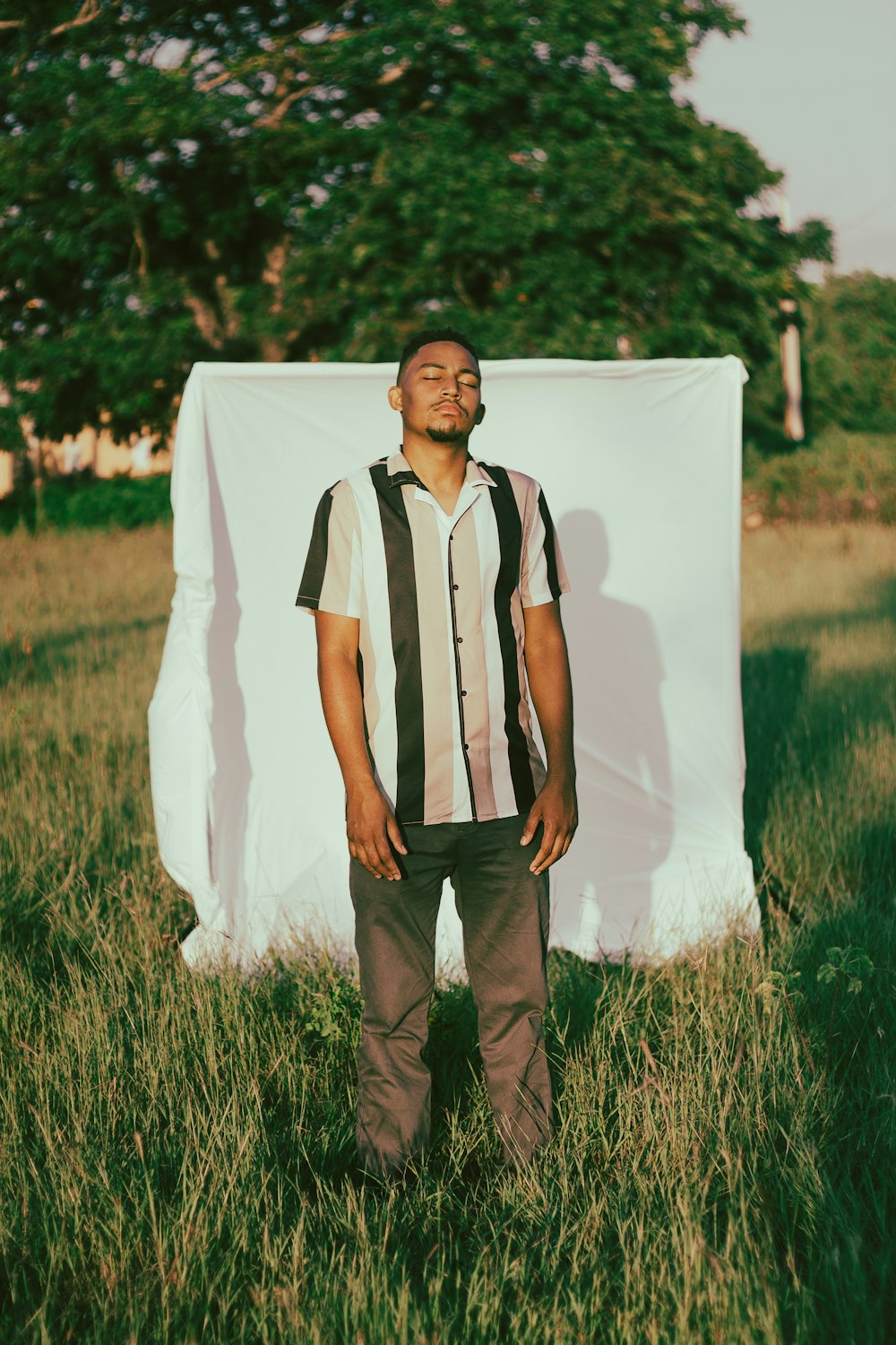 a man standing in a field next to a white sheet