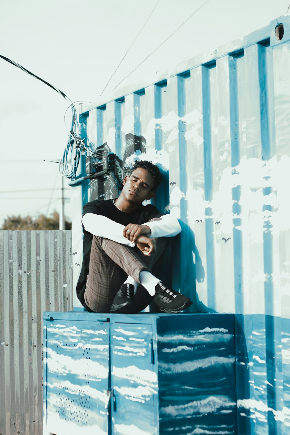 a man sitting on top of a blue container