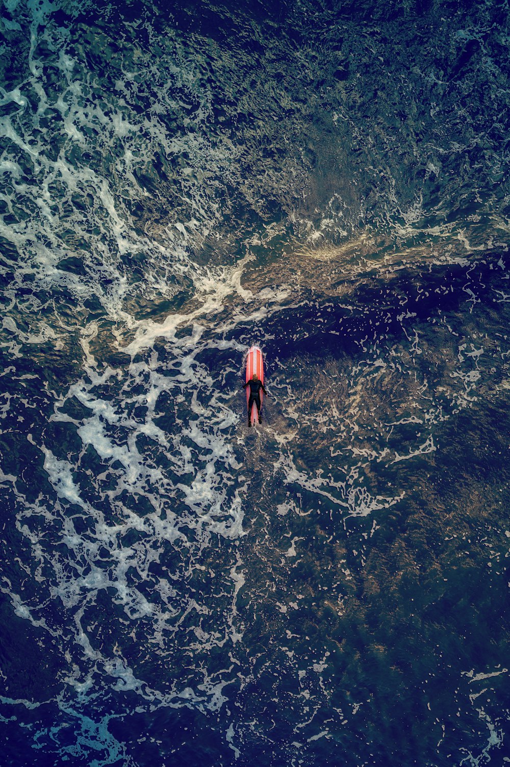 uma pessoa montando uma prancha de surf em cima de um grande corpo de água