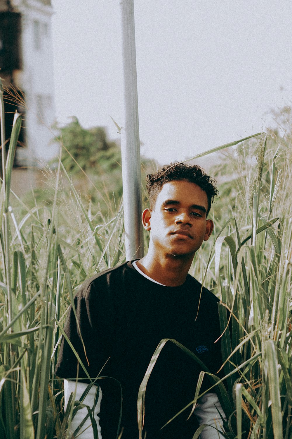 a man sitting in tall grass next to a street sign