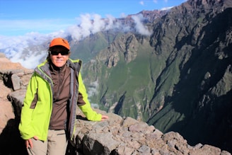 a person standing on a ledge with mountains in the background
