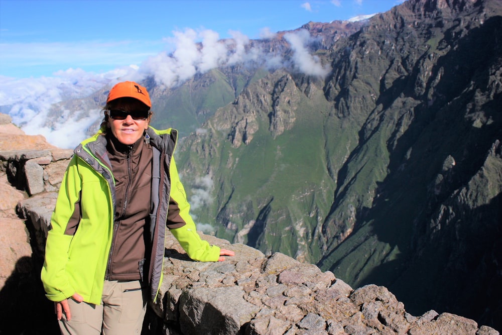 a person standing on a ledge with mountains in the background