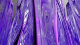 Abstract patterns with swirling vortexes, featuring shades of purple and pink, dominate the visual landscape. The fluid textures create a sense of motion and depth.