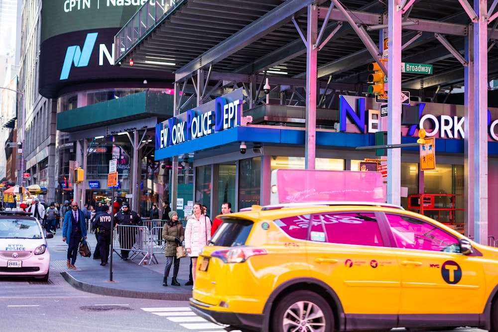 a yellow taxi cab driving down a street next to tall buildings