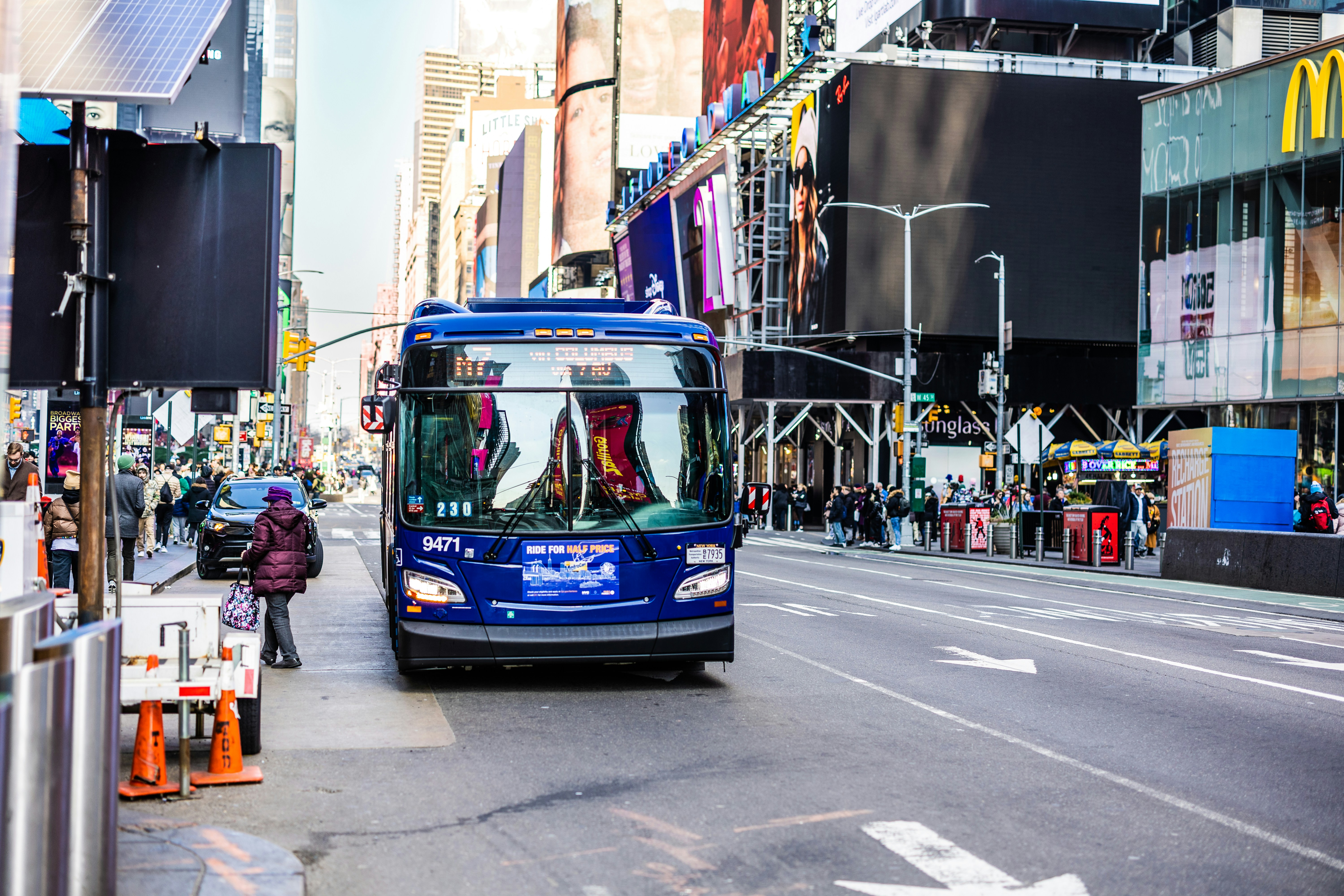 a blue bus driving down a street next to tall buildings