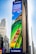A large outdoor advertisement on a skyscraper depicts a family enjoying a water slide. The text on the advertisement reads 'Visit Orlando' and 'Anything is possible if you can imagine it.' The colors are vibrant, including a bright blue sky and a green water slide.
