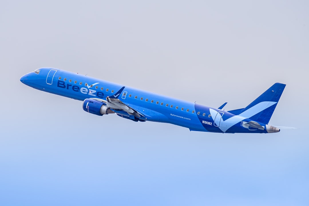 a large blue airplane flying through a blue sky, Breeze Airways Embraer E190 departing RDU Taken by Daniel Shapiro