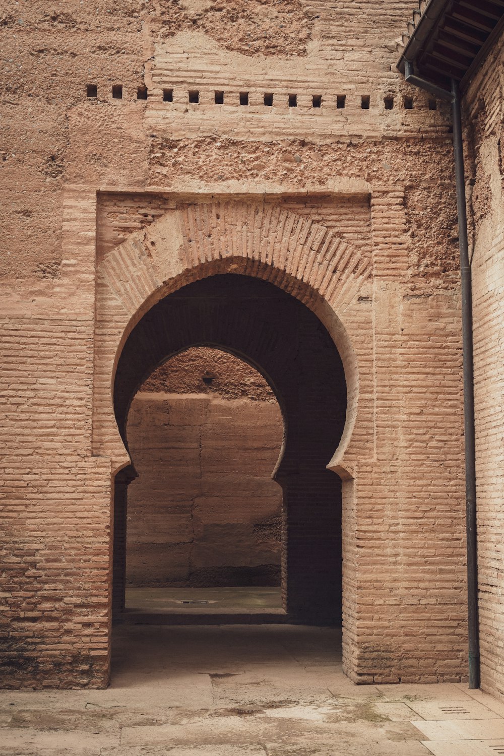 an archway in a brick building with a clock on the wall