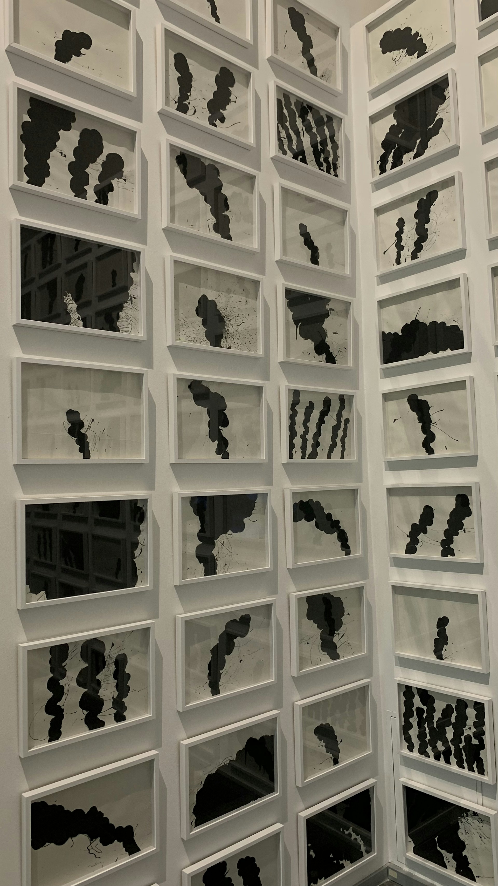 An overhead shot of a collection of geometric art prints arranged in a harmonious grid on a wooden floor.