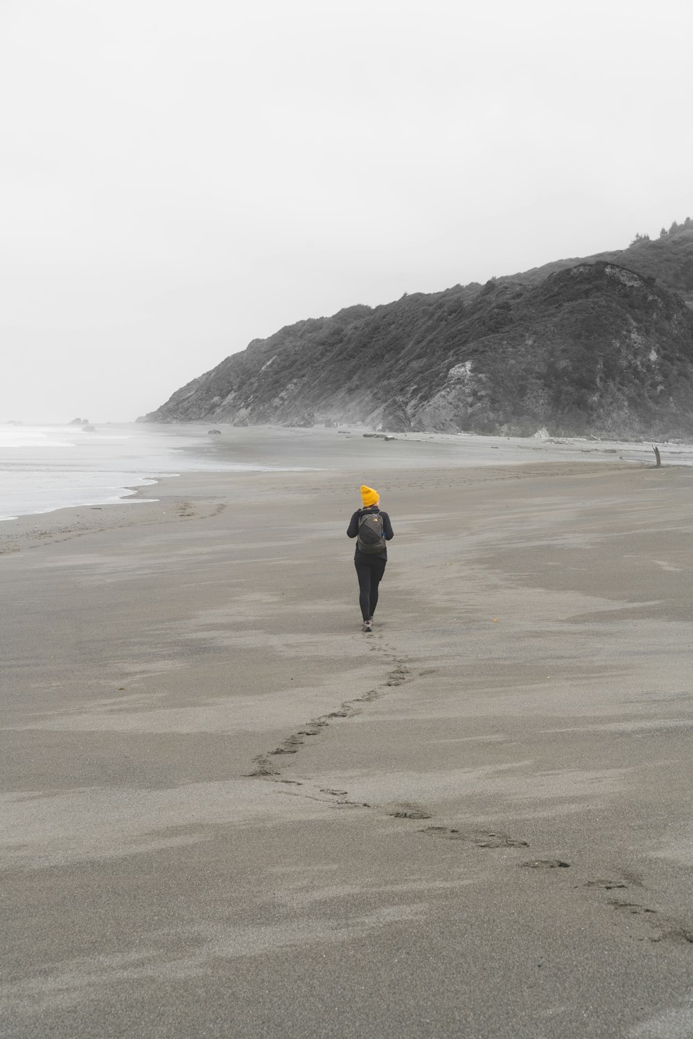a person walking on a beach with a yellow hat