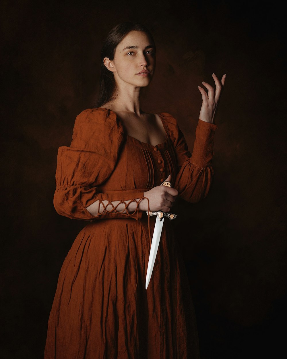 a woman in a brown dress holding a knife