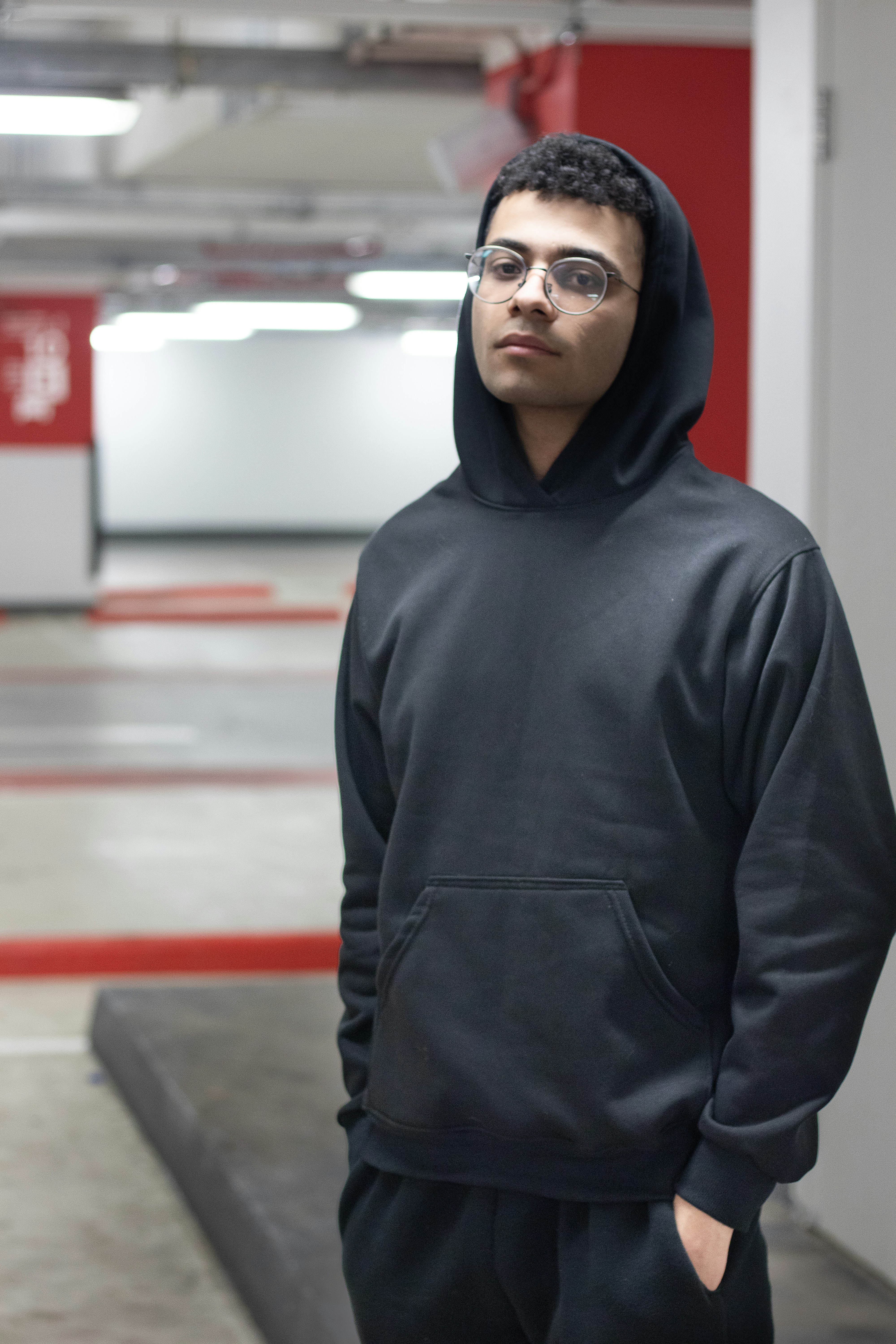 a man in a black hoodie standing in a parking garage