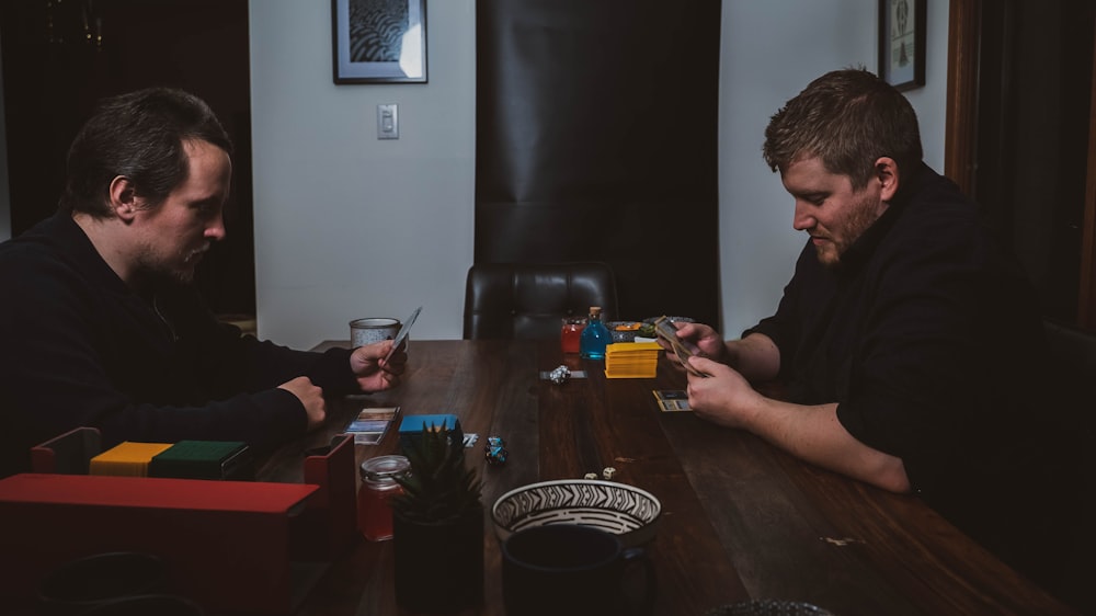 two men sitting at a table playing cards