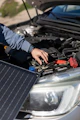Technician inspecting a hybrid car battery in a bright, modern workshop.