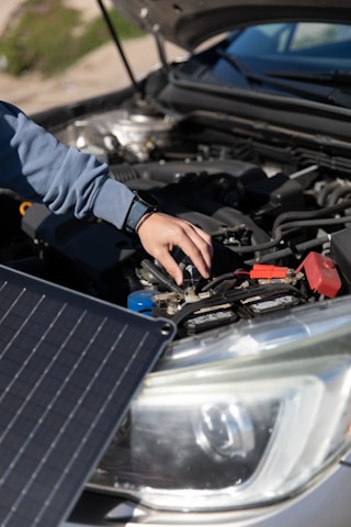 A friendly technician testing a car battery inside a bright, organized warehouse in Al Barsha.