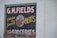 A vintage-style advertisement painted on a brick wall features large text that reads 'G.M. Fields Fresh and Smoked Meats' accompanied by an illustration of a cow's head. The sign also mentions 'Groceries' at the bottom.