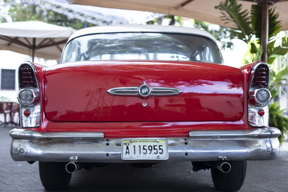 an old red car is parked under an umbrella