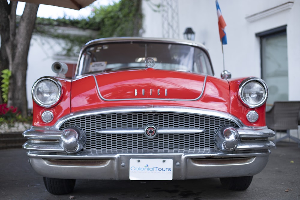 a red classic car parked in front of a building