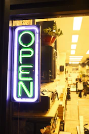 An entrepreneur proudly opening the doors of a new local shop with community members gathered outside.