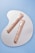 Two elegant gold-colored tubes of eye cream placed on a reflective, irregularly shaped surface. The background is a solid light blue color, enhancing the sophisticated appearance of the products.