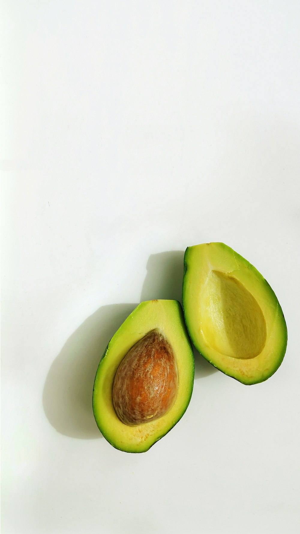 an avocado cut in half on a white surface