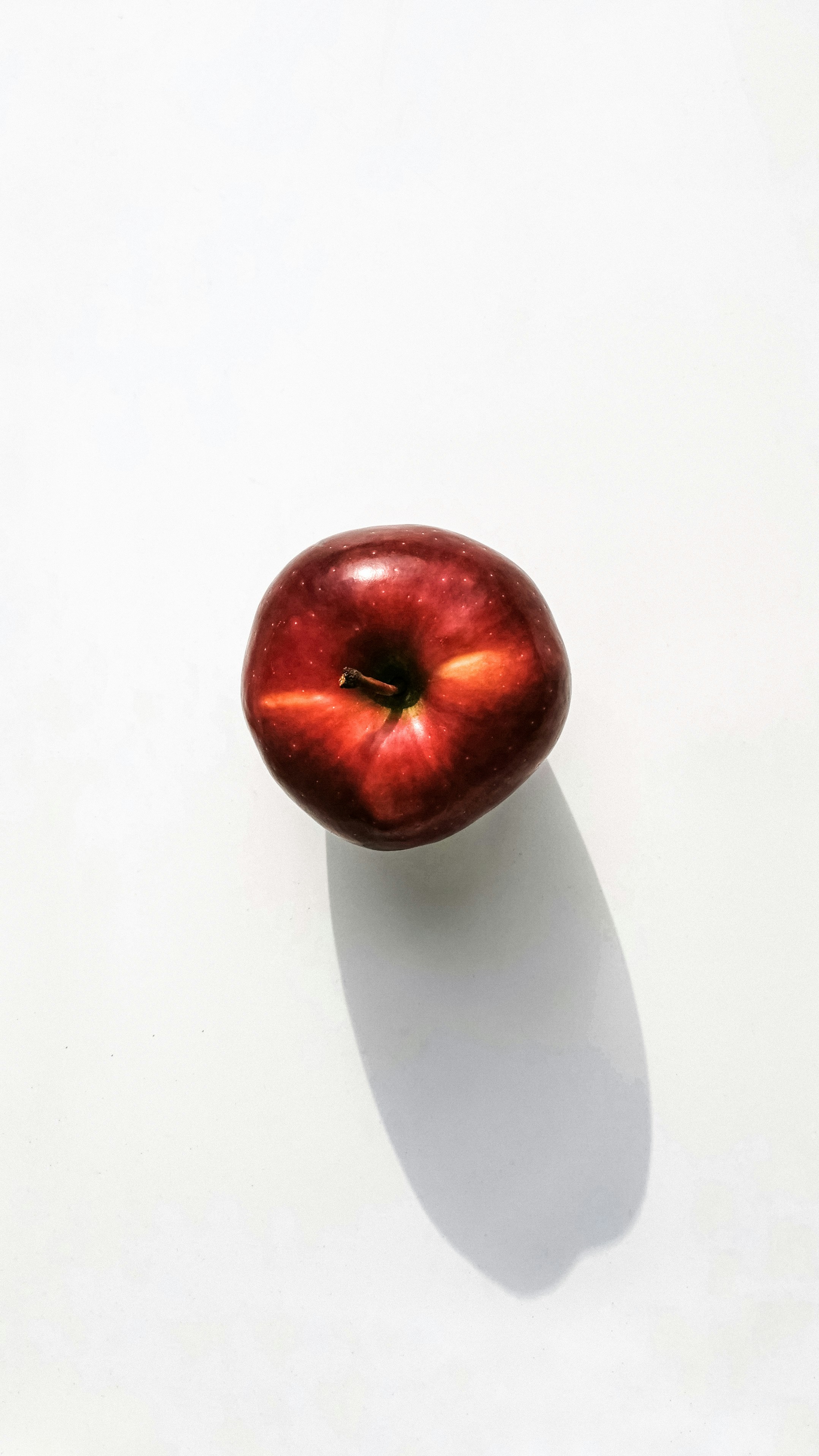 a red apple sitting on top of a white table
