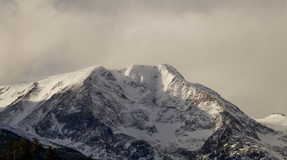 a mountain covered in snow under a cloudy sky