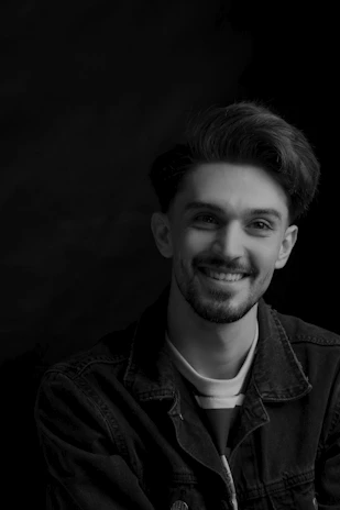 A vibrant portrait of a young man laughing against a soft pastel background.