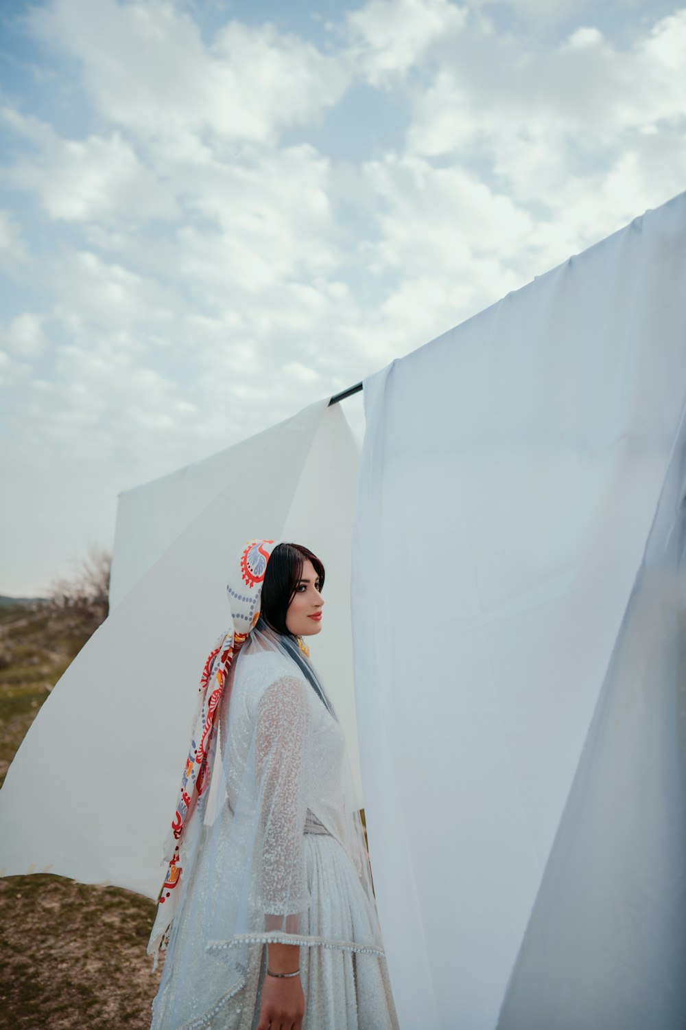 a woman in a white dress standing next to a white sheet