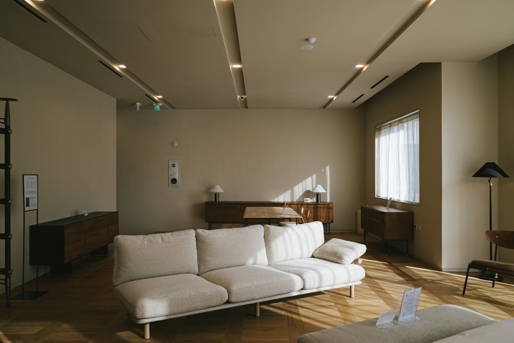 eine weiße Couch in einem Wohnzimmer neben einem Fenster