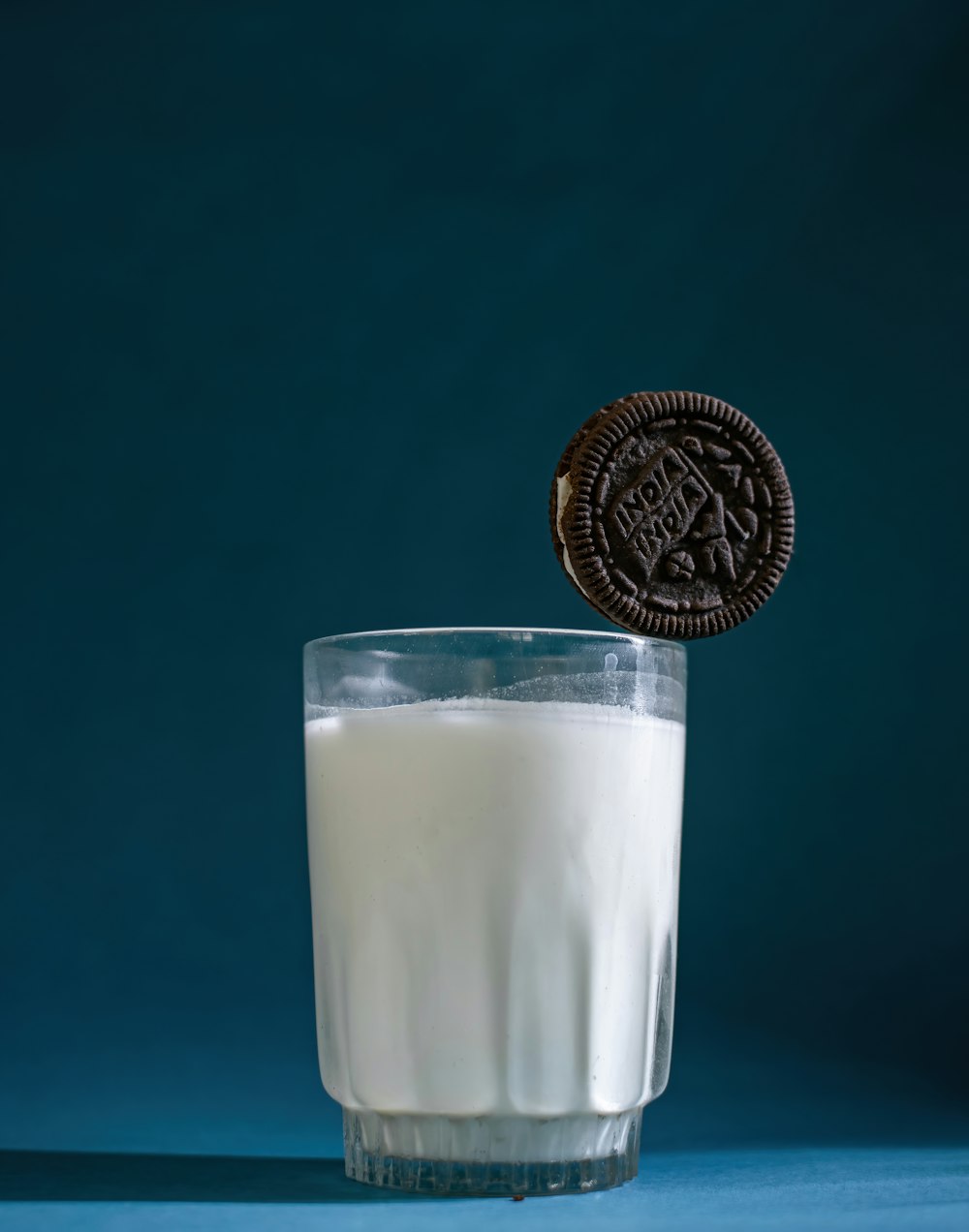 a glass of milk and a cookie on a blue background