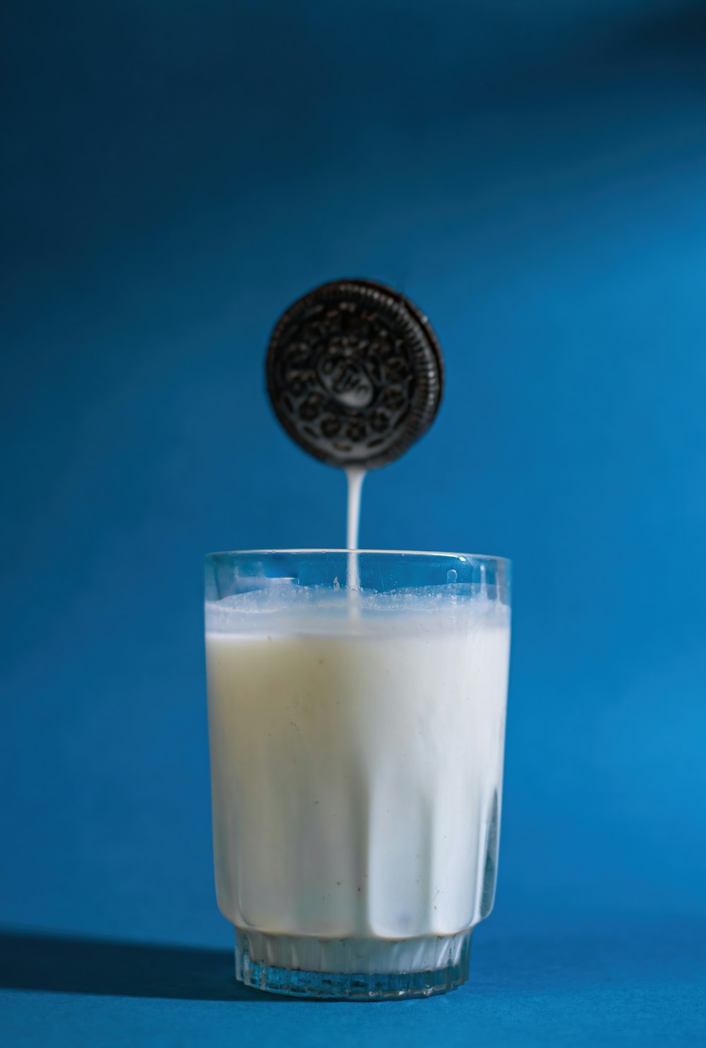 a cookie being poured into a glass of milk