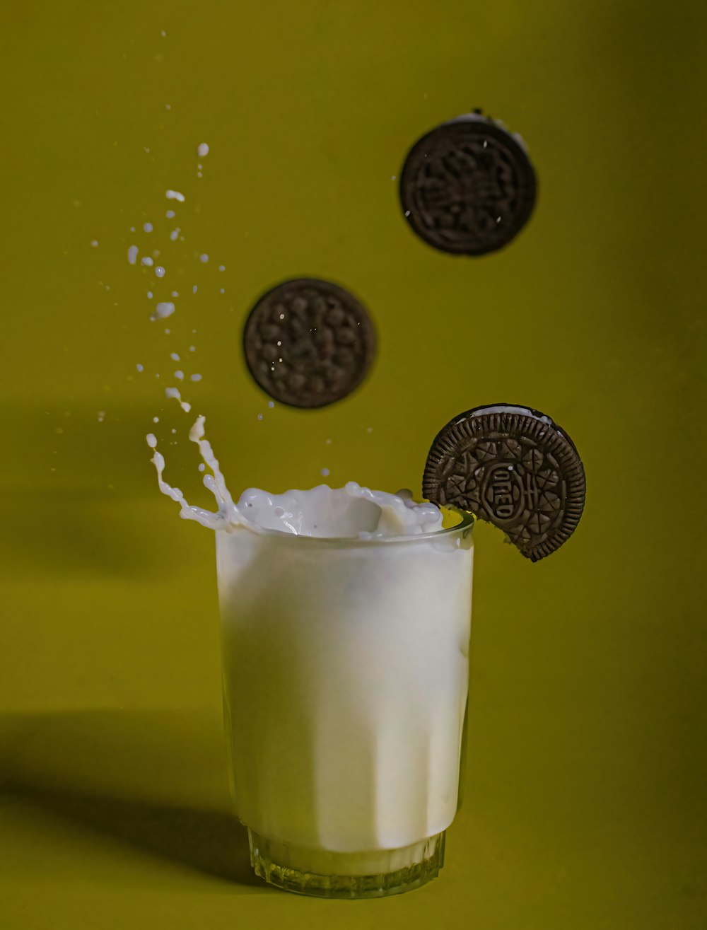 a glass of milk and cookies falling into it