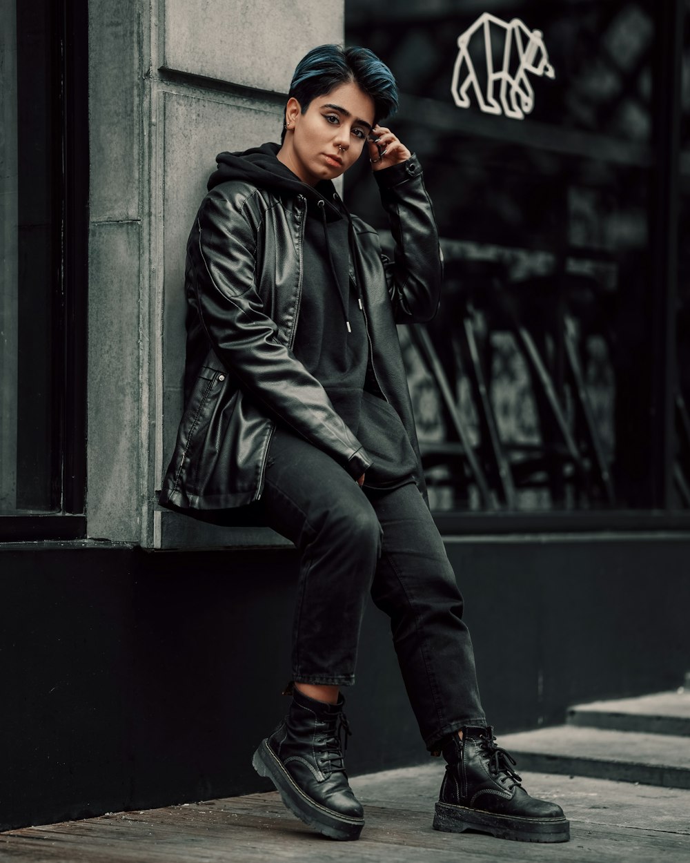 a man in a black jacket sitting on a ledge