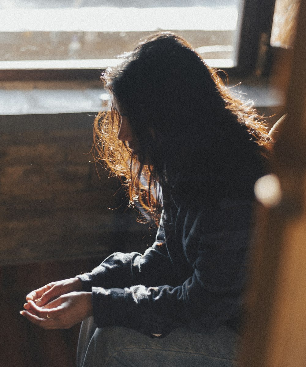 a woman sitting in front of a window next to a window