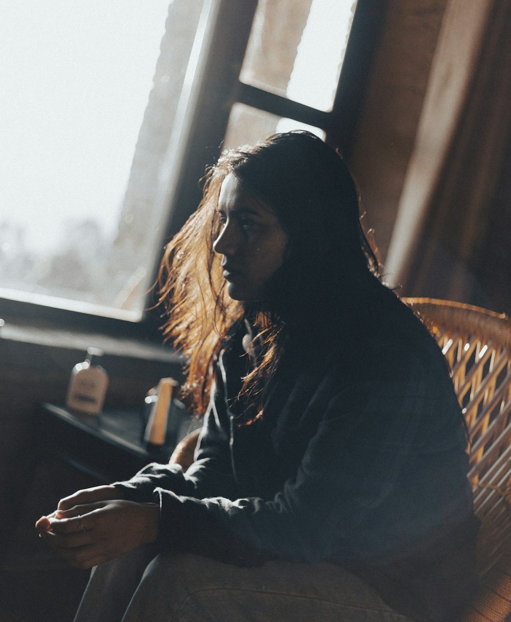 a woman sitting in a chair looking out a window