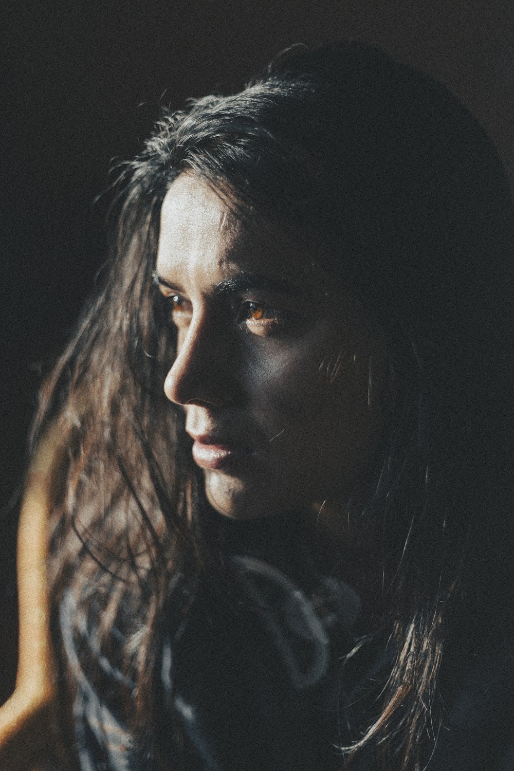 a woman with long dark hair is staring into the distance