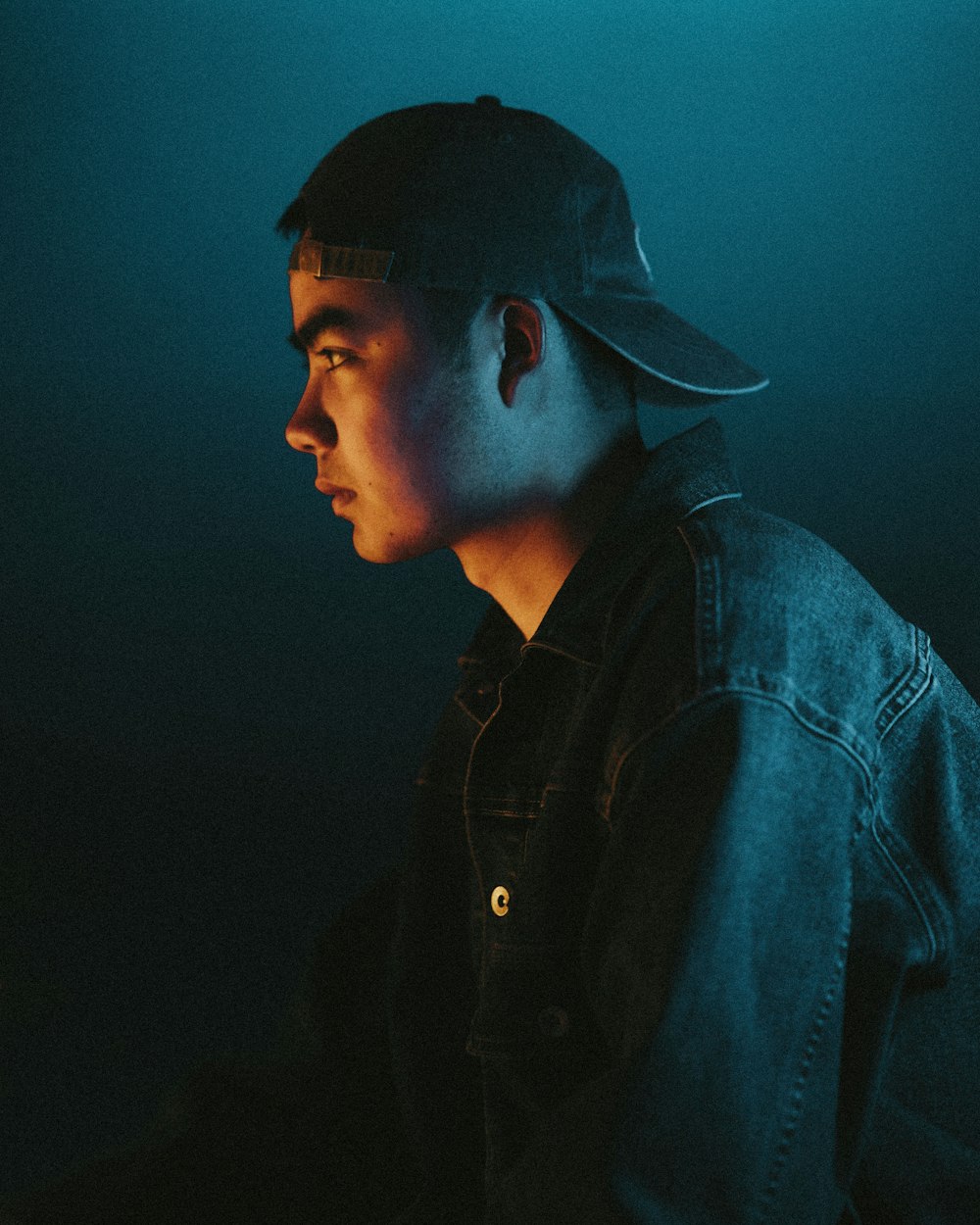 a young man in a denim jacket and baseball cap