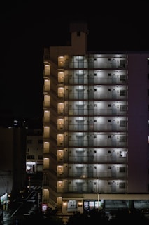 A nighttime exterior shot of a multi-unit property with lights glowing from windows.