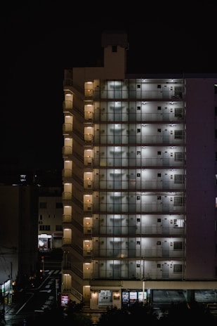 A nighttime exterior shot of a multi-unit property with lights glowing from windows.